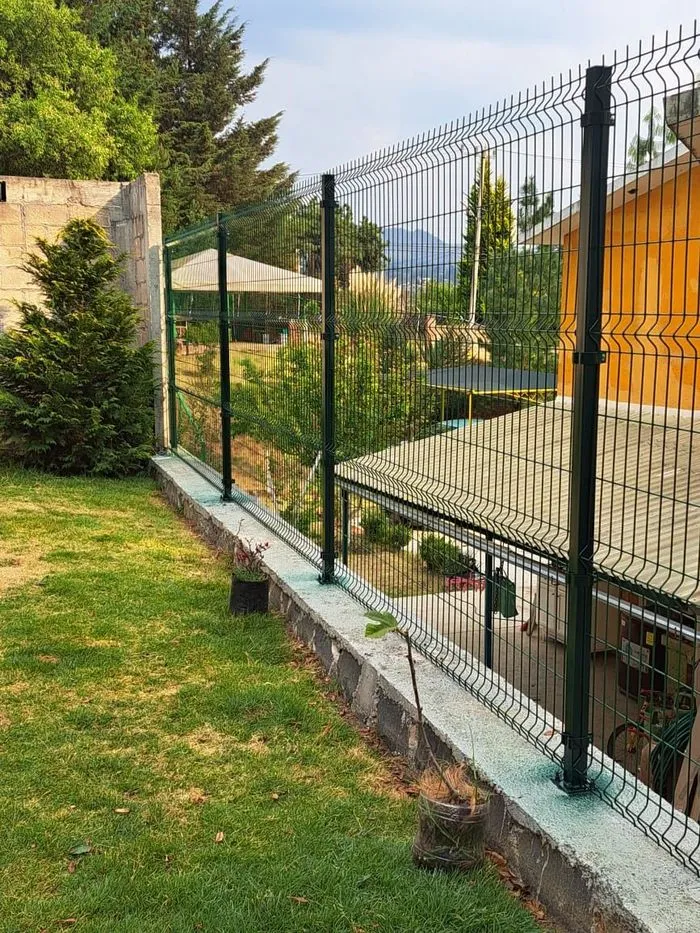 Cerca de panel de malla verde instalada sobre muro en un jardín